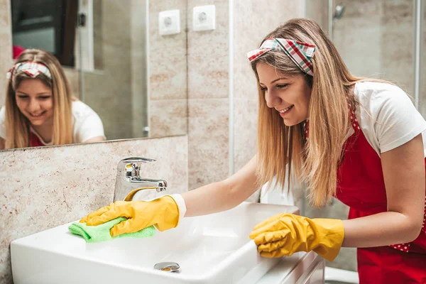 Young and happy woman cleaning house bathroom.