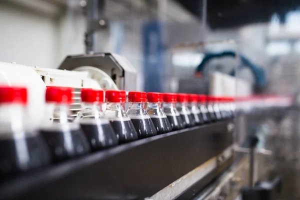 Bottling factory - Black juice bottling line for processing and bottling juice into bottles. Selective focus.