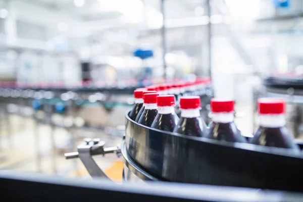 Bottling factory - Black juice bottling line for processing and bottling juice into bottles. Selective focus.