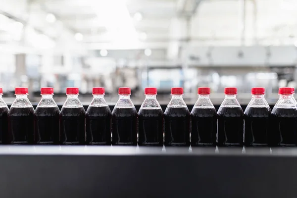 Bottling factory - Black juice bottling line for processing and bottling juice into bottles. Selective focus.