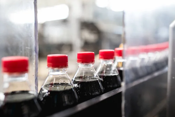 Bottling factory - Black juice bottling line for processing and bottling juice into bottles. Selective focus.