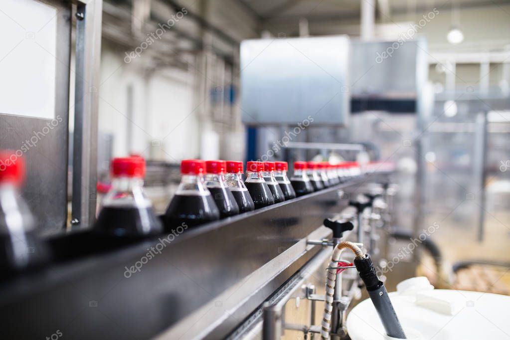 Bottling factory - Black juice bottling line for processing and bottling juice into bottles. Selective focus. 