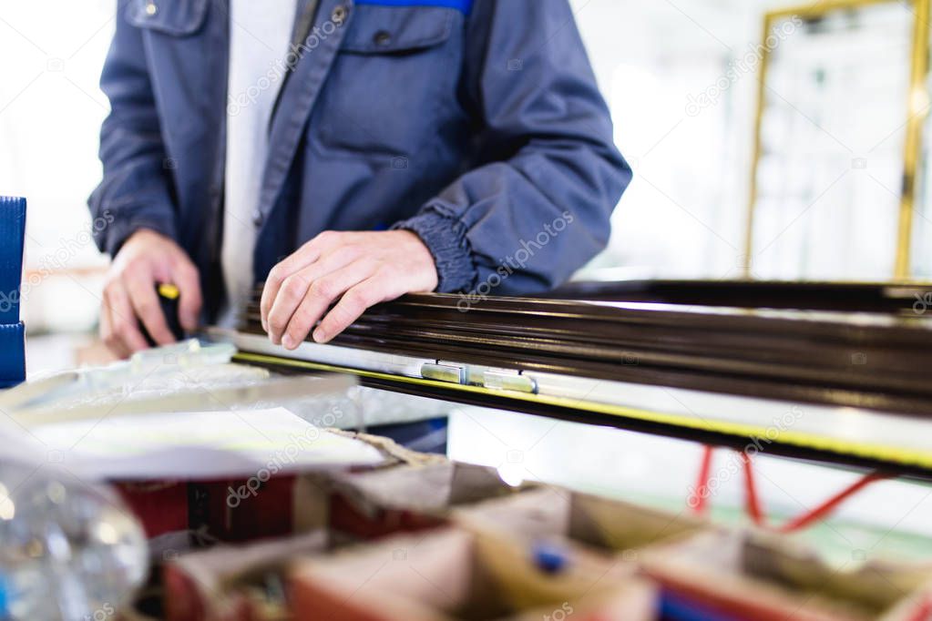 Factory for aluminum , wooden and PVC windows and doors production. Manual worker assembling PVC doors and windows. Selective focus. 