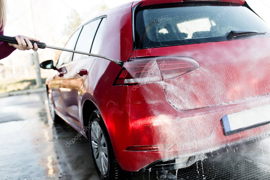 Car washing. Cleaning car using high pressure water. Selective focus. 