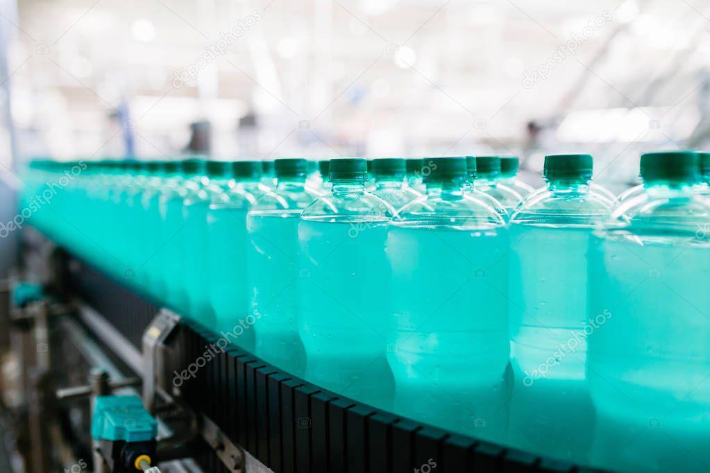 Bottling plant - Water bottling line for processing and bottling carbonated water into green bottles. Selective focus. 