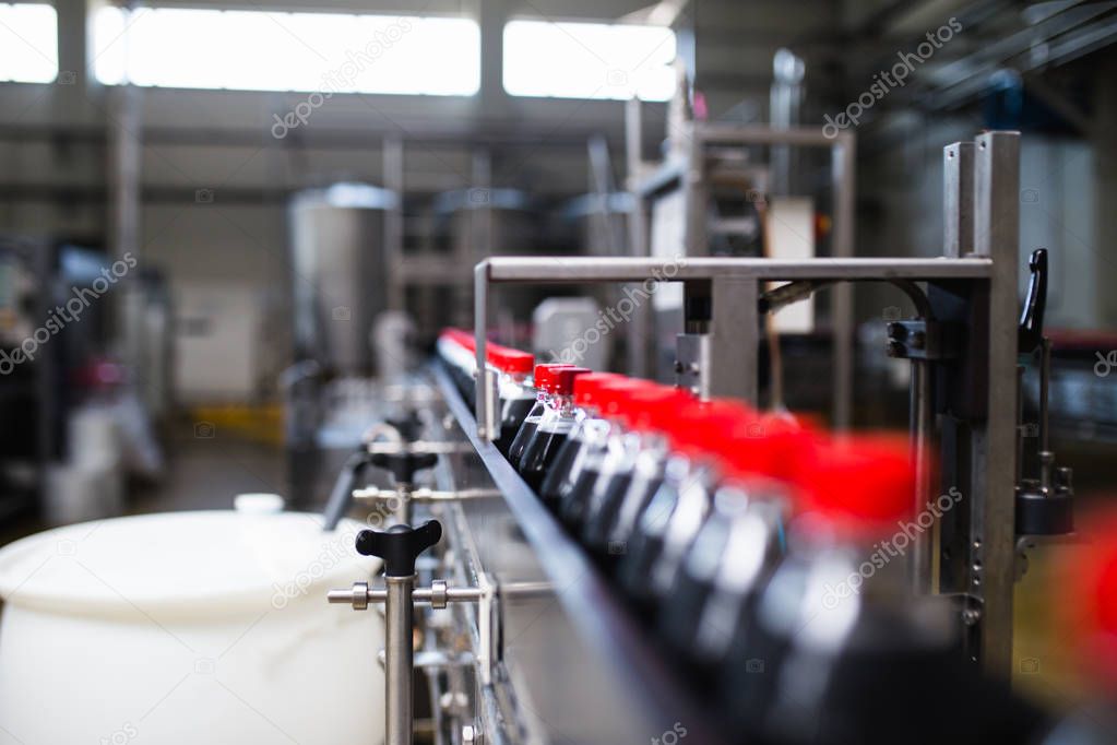 Bottling factory - Black juice bottling line for processing and bottling juice into bottles. Selective focus. 
