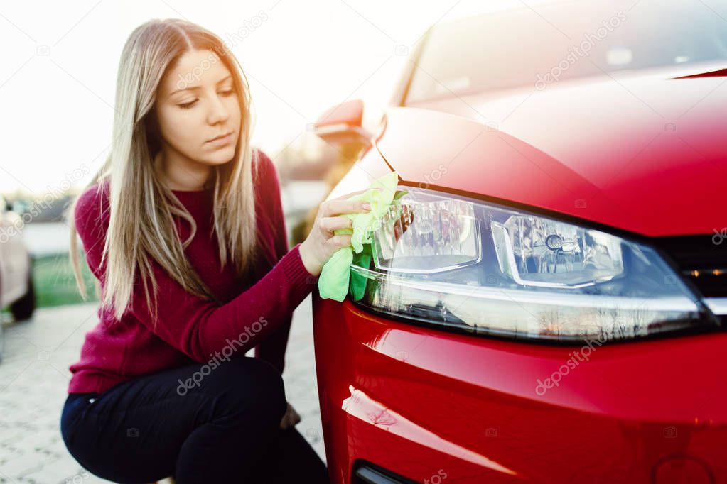 Young woman cleaning car with microfiber cloth, car detailing (or valeting) concept. 