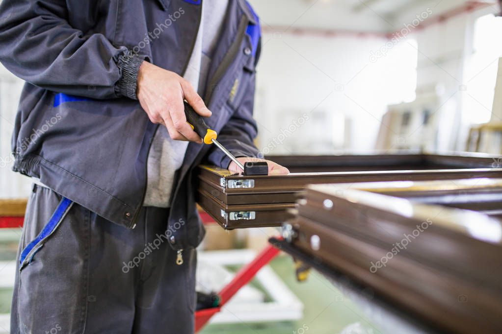 Factory for aluminum , wooden and PVC windows and doors production. Manual worker assembling PVC doors and windows. Selective focus. 