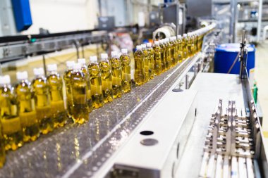 Şişeleme fabrikası - elma suyu şişeleme hattı işleme koymak ve şişelere meyve suyu doldurmak için. Seçici odak.