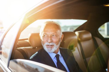 Limuzininde oturan kıdemli iş adamı. İş konsepti. Arka ışık.