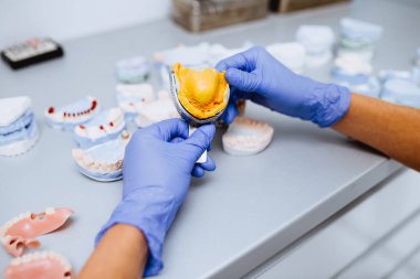 Diş protezi, protez. Takma diş üzerinde çalışırken protezin ellerini kapat. Seçici odak.