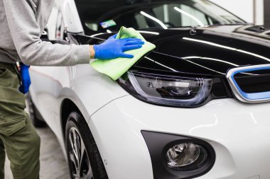 Elektrikli arabayı mikrofiber bezle temizleyen adam, araba temizleme konsepti. Seçici odak. 