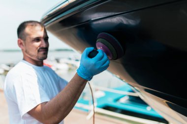 Tekne bakımı - Yörüngesel cilalama teknesi olan bir adam marinada. Seçici odak.