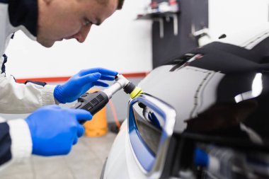 Araba temizleme - Oto tamir atölyesinde orbital cilası olan bir işçi.  