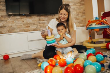 Genç ve mutlu bir anne, küçük oğluyla evde oynuyor.