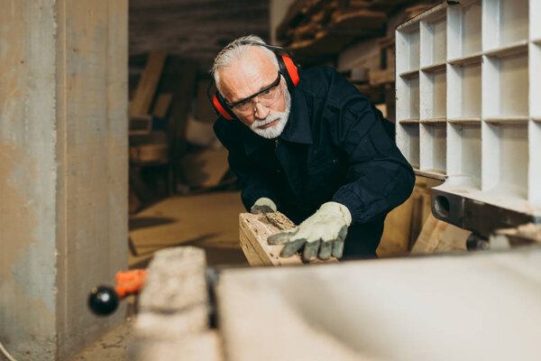 Senior master carpenter working in his woodwork or workshop.