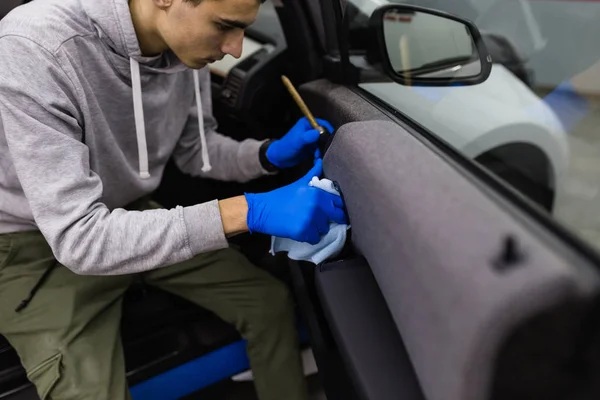 A man cleaning car interior, car detailing (or valeting) concept. Selective focus.