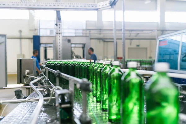 处理纯矿泉水并将其装瓶成绿色玻璃瓶的装瓶生产线 有选择的重点 — 图库照片