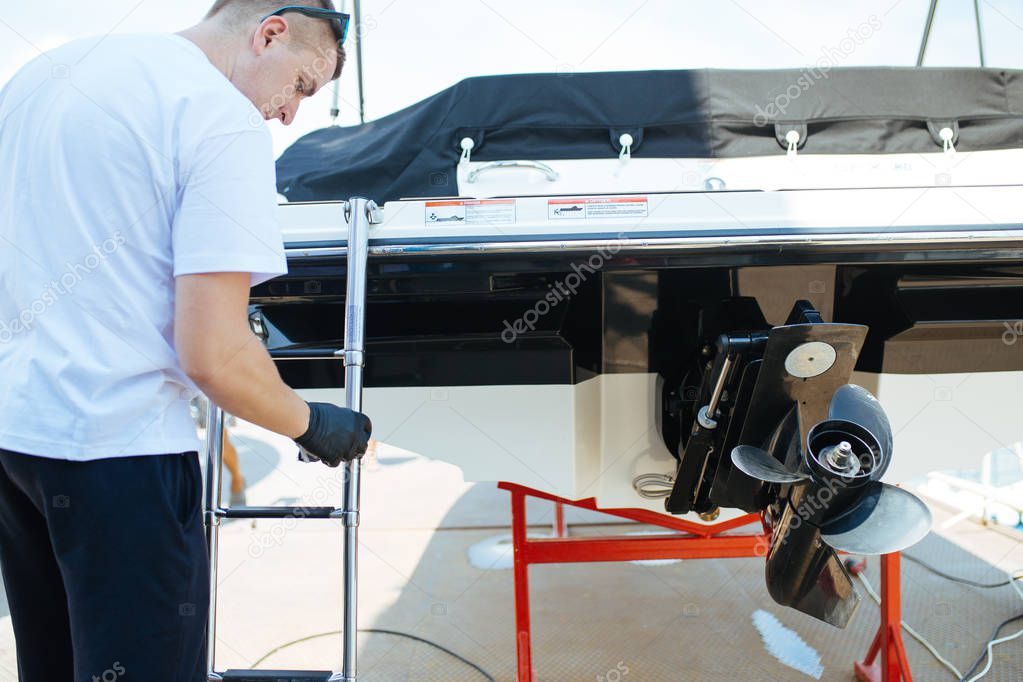 Boat maintenance - A man cleaning boat with cloth. Selective focus.