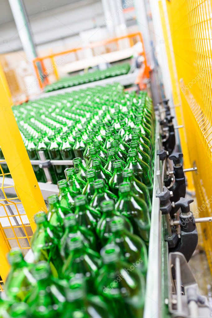 Water factory - Water bottling line for processing and bottling pure spring water into green glass small bottles. Selective focus.