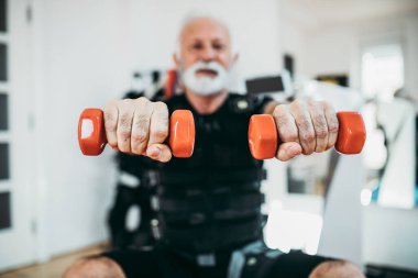 Yakışıklı ve pozitif kıdemli bir adam elektriksel kas stimülasyonu için egzersiz yapıyor..