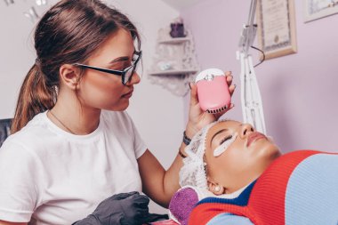 Kirpik uzatma işleminde güzel bir genç kadın. Kozmetik ve vücut bakımı kavramı.
