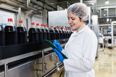 Fabrikada panosu olan gülümseyen genç bir kadın eczacı.