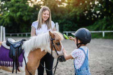 Şirin küçük kız ve ablası çiftlikte midilli atıyla eğleniyorlar..