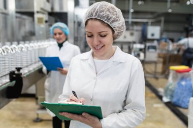 Şişeleme fabrikasındaki kadın işçiler sevkiyattan önce su şişelerini kontrol ediyorlar. Denetim kalite denetimi. 