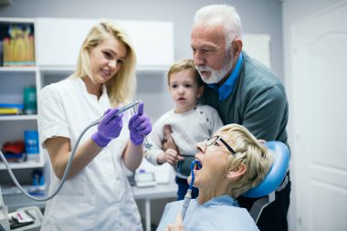 Dişçi klinikte bir hastayı muayene ediyor.