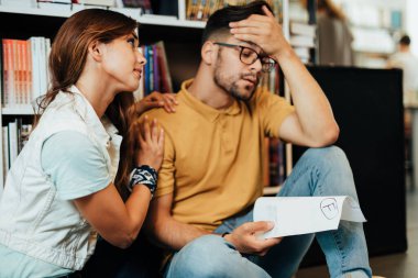 Başarısız bir sınavdan sonra üniversite kütüphanesinde oturan iki çekici ve yorgun öğrenci..  