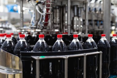 Şişeleme fabrikası, şişelere meyve suyu işlemek ve şişelemek için kullanılıyor. Seçici odak. 