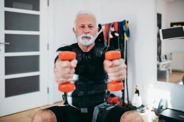 Yakışıklı ve pozitif kıdemli bir adam elektriksel kas stimülasyonu için egzersiz yapıyor..