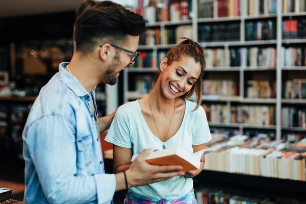 Attractive young students man and woman choosing books in the bookstore