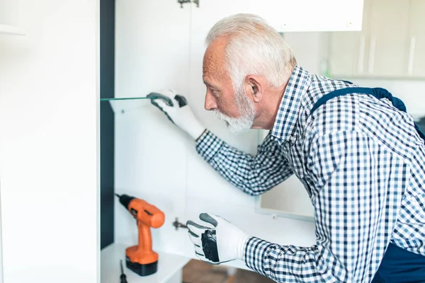 Senior handyman working in the kitchen. Renovation.