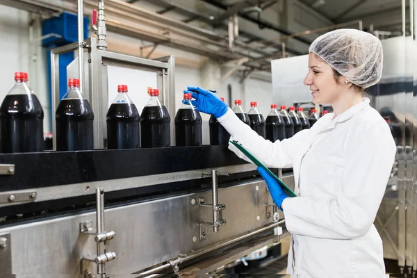 Ung Glad Kvinnlig Arbetare Buteljeringsfabriken Kontrollerar Juiceflaskor Före Leverans Kvalitetskontroll — Stockfoto