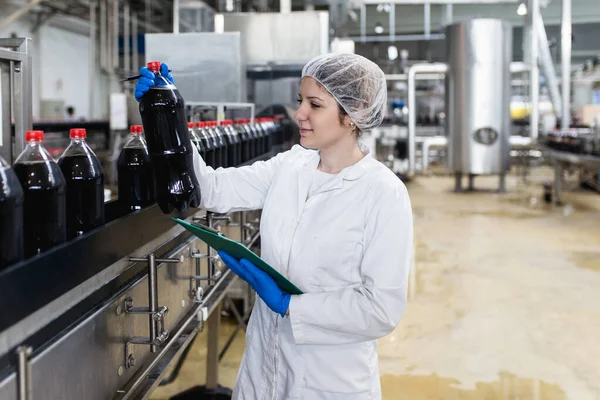 Jonge Vrolijke Vrouwelijke Werknemer Bottelfabriek Controleert Sapflessen Voor Verzending Inspectiekwaliteitscontrole — Stockfoto