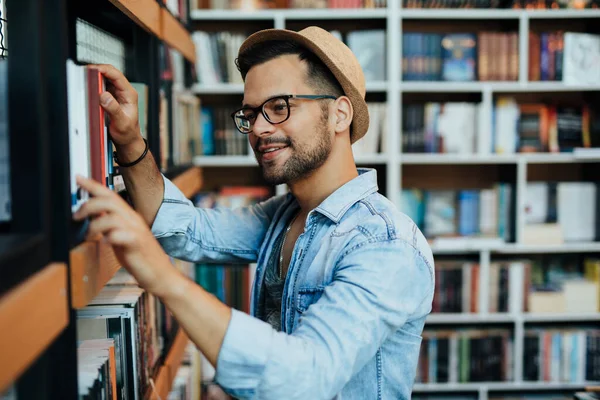 書店で本を選ぶ魅力的な若い男性学生 — ストック写真