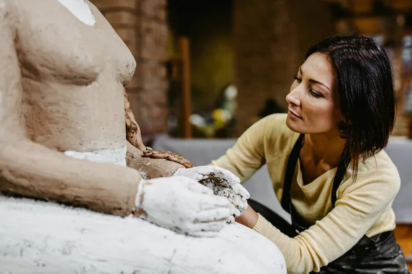 Beautiful middle age woman professional sculptor working on gorgeous sculpture.