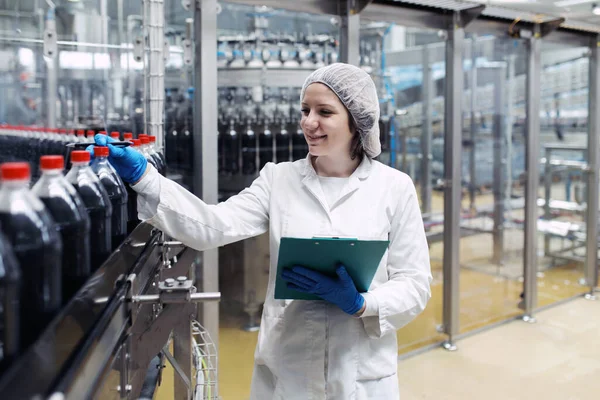 Jonge Vrolijke Vrouwelijke Werknemer Bottelfabriek Controleert Sapflessen Voor Verzending Inspectiekwaliteitscontrole Stockfoto