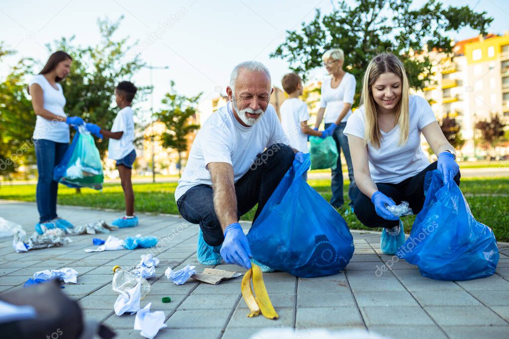 Volunteers with garbage bags cleaning up garbage outdoors - ecology concept.