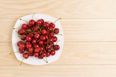 Beyaz tabak dolusu masa üstü görünümünde olgun kiraz