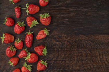 Bir sürü ahşap arka plan üzerinde dağınık olgun çilek. Metin için yer