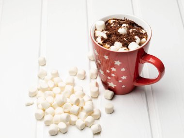 Sıcak kakao ve masanın üzerine dağılmış marshmallow ile kırmızı kupa.