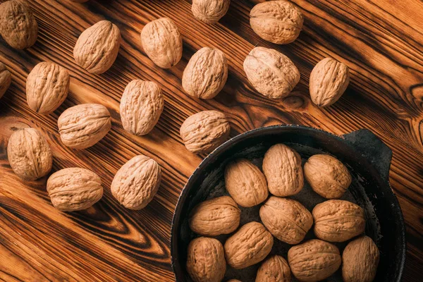 Грецкие орехи сверху в сковороде и на деревянном столе — стоковое фото