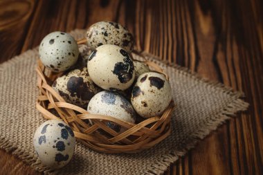 Jüt kumaş ve ahşap arka plan üzerinde bir sepet taze bıldırcın yumurta