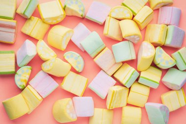 Pembe arka planda farklı renklerde rastgele yatan marshmallow'un üst görünümü