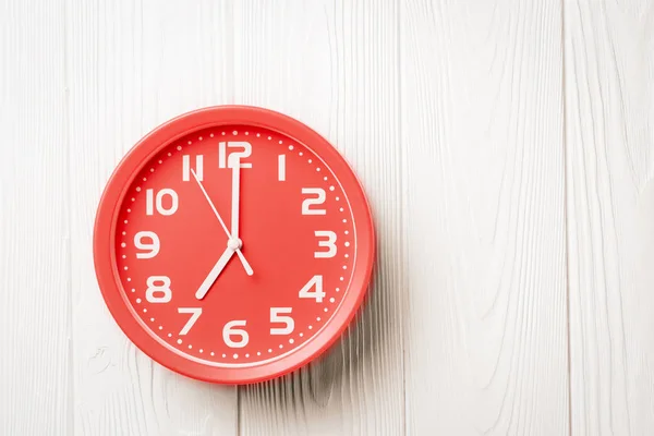흰색 나무 배경에 7시를 보여주는 탑 뷰 빨간 시계 — 스톡 사진