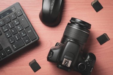 Masaüstünde bellek kartları olan modern bir dijital fotoğraf makinesinin ve klavyenin üst görünümü