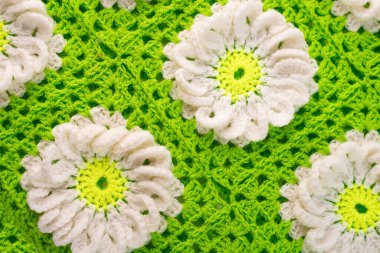 Örülmüş yün ipliklerin deseni yapraklarla çiçekler oluşturuyor..